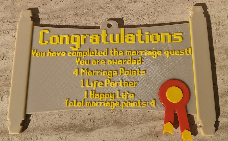 May include: A beige scroll-shaped plaque with yellow pixelated text reading: Congratulations, You have completed the marriage quest! You are awarded: 4 Marriage Points, 1 Life Partner, 1 Happy Life, Total marriage points: 4. A red and yellow ribbon is attached.