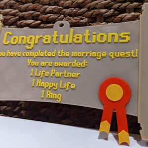 May include: A beige scroll-shaped plaque with yellow pixelated text reading: Congratulations, You have completed the marriage quest! You are awarded: 1 Life Partner, 1 Happy Life, 1 Ring. A red and yellow ribbon emblem is attached to the bottom right.