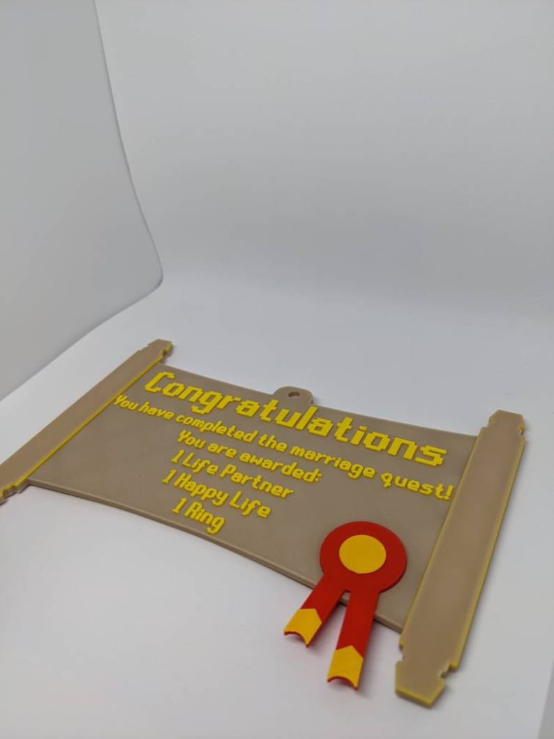 May include: A tan, scroll-shaped plaque featuring yellow, pixelated text that reads: Congratulations, You have completed the marriage quest! You are awarded: 1 Life Partner, 1 Happy Life, 1 Ring. A red and yellow ribbon emblem is attached.
