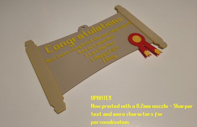 May include: A beige scroll-shaped plaque with yellow text reading Congratulations, You have completed the marriage quest, You are awarded 1 Life Partner, 1 Happy Life, 1 Ring. It features a red and yellow ribbon emblem and a small hanging loop.