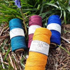 May include: Four spools of hemp cord in different colours: teal, burgundy, blue, and yellow. The spools are labelled "Hemp Cord" and "Hemptique".