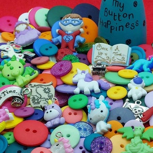 May include: A colourful assortment of buttons, charms, and other craft supplies. The buttons are in various colours, shapes, and sizes. There are also several charms, including a unicorn, a dragon, and a pirate skull. The text "My Button Happiness" is visible on a wooden doll.