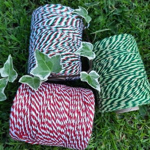 May include: Three spools of twine with gold glitter accents. One spool is red and white, one is green and white, and one is green and gold.