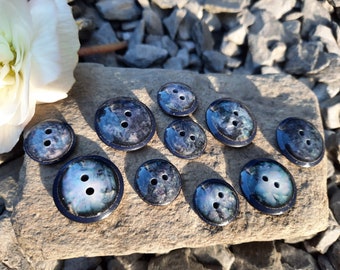 May include: Nine dark blue buttons with a white and black marbled design. The buttons have two holes each.