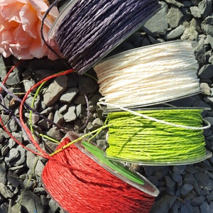 Può includere: Quattro bobine di spago di diversi colori: rosso, verde, bianco e viola. Lo spago è avvolto attorno a bobine di plastica trasparente.