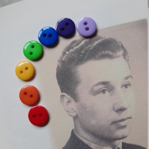 May include: A rainbow of colorful buttons arranged in a semi-circle on a white background. The buttons are red, orange, yellow, green, blue, indigo, and violet.