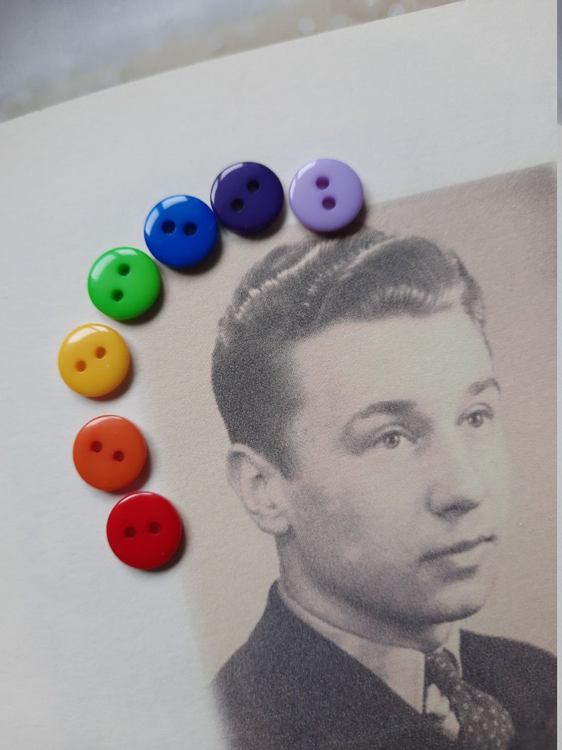May include: A rainbow of colorful buttons arranged in a semi-circle on a white background. The buttons are red, orange, yellow, green, blue, indigo, and violet.