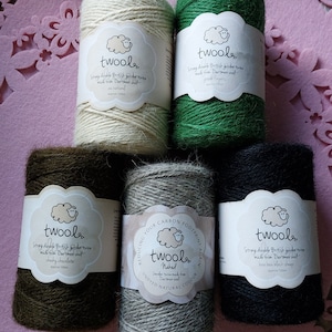 May include: Five spools of natural twine made from Dartmoor wool. The twine is available in natural, green, brown, grey, and black. Each spool has a label with the brand name "twool" and a sheep illustration. The label also includes information about the twine, such as its origin and length.