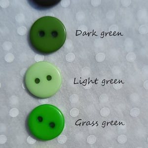 May include: Five round plastic buttons in various shades of green, from darkest green to neon green. Each button has two holes.