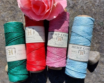 Peut inclure: Quatre bobines de cordon de chanvre de différentes couleurs : vert, rouge, rose et bleu. Chaque bobine porte une étiquette indiquant "Hemp Cord" et "Hemptique".