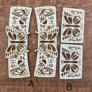 May include: Three wooden plaques with laser-cut butterfly designs. The plaques are in a light wood color with brown butterfly designs. The plaques are labeled A and B.