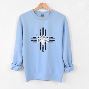 Peut inclure: Un sweat-shirt bleu clair avec un crâne blanc et un motif floral sur un symbole sud-ouest noir et blanc.