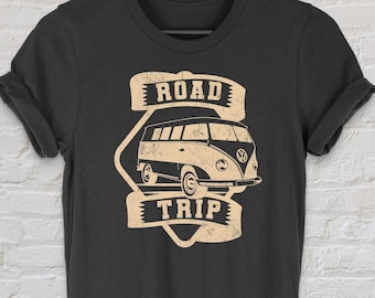 Op de afbeelding: Zwart T-shirt met een vintage-stijl grafische afbeelding van een busje met de tekst "Road Trip" erop.