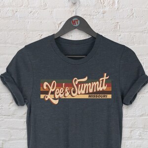 Puede incluir: Camiseta de color gris oscuro jaspeado con un gráfico de estilo vintage que dice "Lee's Summit, Missouri".