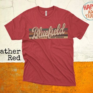 Puede incluir: Camiseta roja heather con un gráfico de estilo vintage que dice "Bluefield West Virginia".