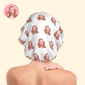 May include: White shower cap featuring a repeating pattern of a woman's face blowing a kiss. The woman has blonde hair and is wearing a white top. The shower cap is on a person's head.