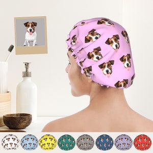 May include: A pink satin shower cap with a repeating pattern of a dog's face. The dog has brown and white fur. The shower cap is shown on a person's head.