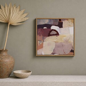Pu&ograve; includere: Dipinto di arte astratta in una cornice di legno con una tavolozza di colori neutri beige, marrone e bordeaux. Una foglia di palma secca in un vaso marrone e una piccola ciotola su una superficie bianca.
