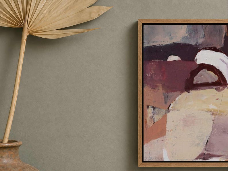 Pu&ograve; includere: Stampa artistica astratta in una cornice di legno naturale. L'opera presenta una miscela di toni bordeaux, crema e beige. Una foglia di palma secca e un vaso di terracotta sono in primo piano.