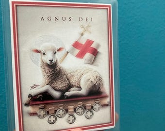 May include: A white lamb with a red cross flag and the text "Agnus Dei" on a white background. The lamb is lying on a red book with gold crosses.