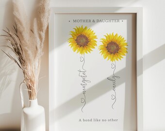 May include: A white framed print with the text "Mother & Daughter" and two yellow sunflowers. The sunflowers have the names "Margaret" and "Emily" written underneath them. The text "A bond like no other" is at the bottom of the print.