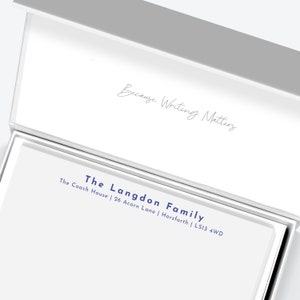 May include: A white box with a grey lid. The lid is open and the inside of the box is white. The box has a blue inscription that reads "The Langdon Family The Coach House | 26 Acorn Lane | Horsforth | LS13 4WD". The lid has a handwritten inscription that reads "Because Writing Matters".
