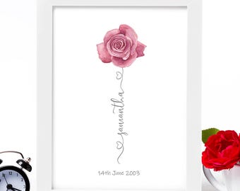 May include: A white framed print with a pink watercolor rose and the name Samantha written in cursive with hearts. The date 14th June 2003 is printed below the name.