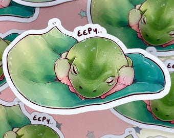 Könnte beinhalten: Eine Sammlung von Aufklebern mit einem niedlichen grünen Frosch, der auf einem Seerosenblatt ruht. Der Frosch hat rosa Akzente und geschlossene Augen, mit dem Text "E€P4.." darüber. Die Aufkleber haben einen weißen Rand und sind auf einem rosa Hintergrund.