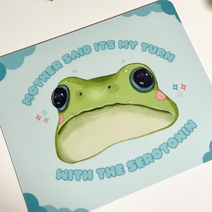 May include: A light blue mousepad with a cartoon frog and the text "Mother said it's my turn with the serotonin".
