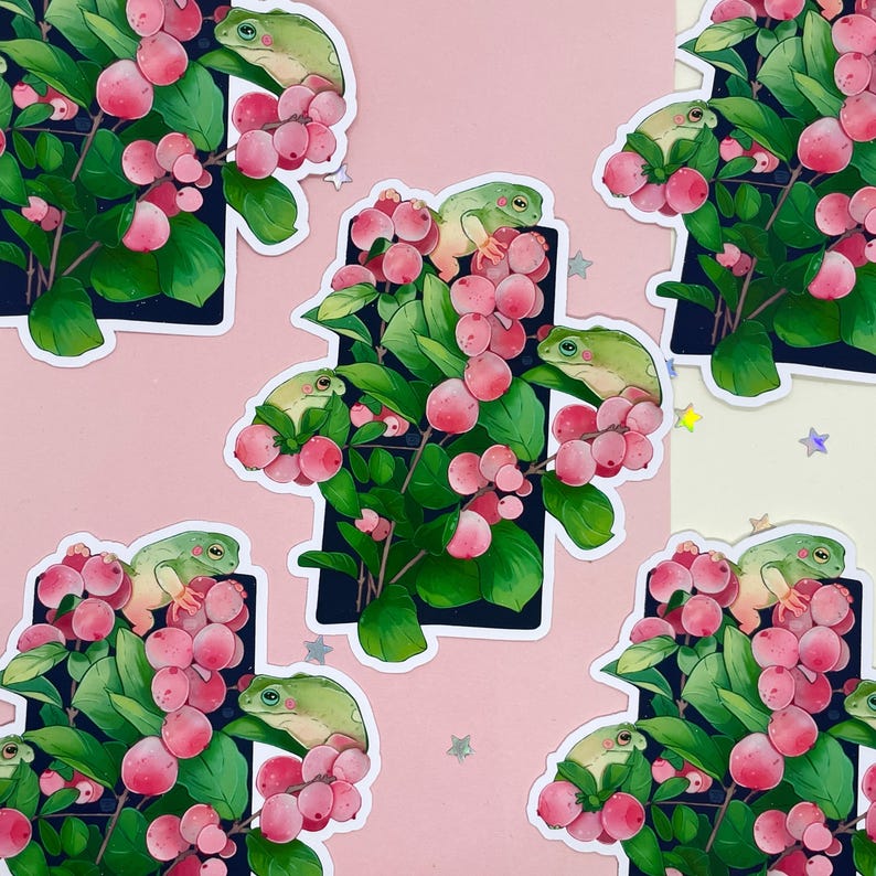 Puede incluir: Patr&oacute;n repetido de pegatinas con ranas verdes posadas en ramas con bayas rosas y hojas verdes. Las pegatinas est&aacute;n colocadas sobre un fondo rosa con acentos en forma de estrella dispersos.