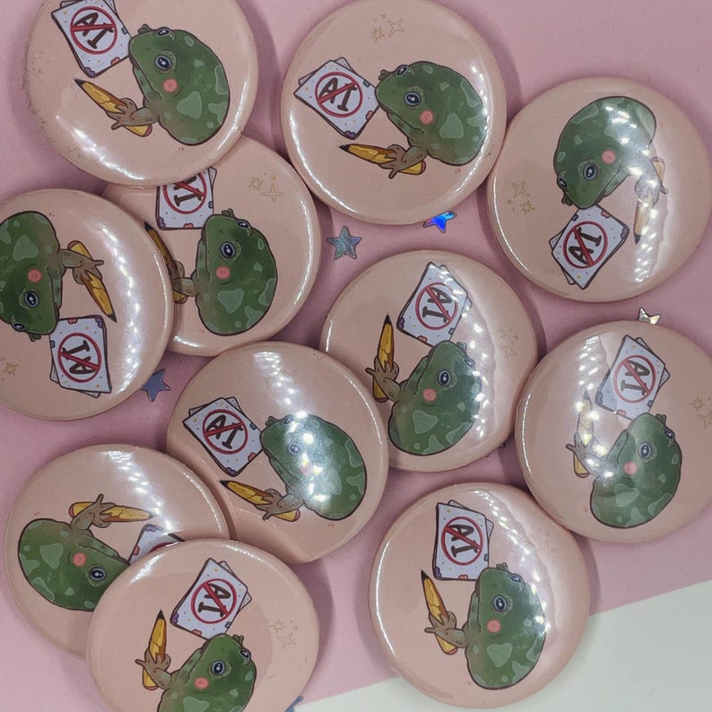 May include: A set of ten pink and white button pins featuring a green frog holding a red and white sign that says "A+." The frog is holding a pencil in its other hand.
