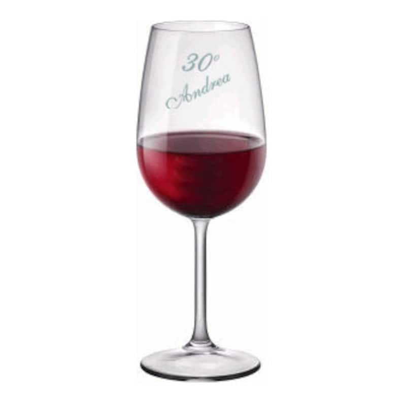 May include: A clear wine glass filled with red wine. The glass has a long stem and a rounded bowl. The text "30&deg; Andrea" is printed on the glass in a light blue color.
