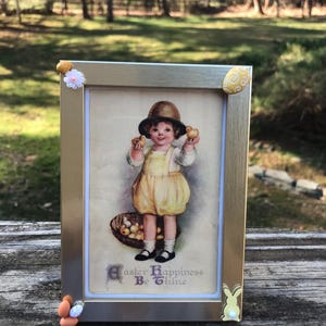 Cartão postal de Páscoa vintage emoldurado com uma garotinha preciosa exibindo alegremente sua cesta de Páscoa com pintinhos