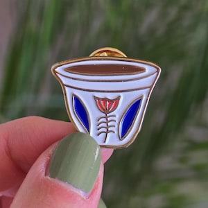 Może przedstawiać: Złota szpilka emaliowana w kształcie tradycyjnej tureckiej filiżanki do kawy z niebiesko-białym wzorem kwiatowym.