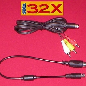 Puede incluir: Cables AV negros para la consola de videojuegos Sega 32X. Los cables incluyen conectores RCA rojos, blancos y amarillos, y un conector negro. El logotipo de Sega 32X y el texto "32X" están en un rectángulo amarillo.