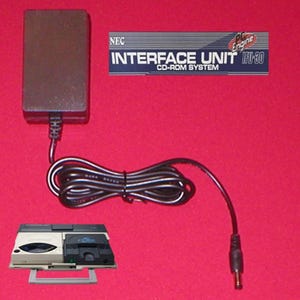 May include: An NEC Interface Unit IFU-30 CD-ROM System with a black power adapter and cable. The system is shown with a console on a red background. The text "INTERFACE UNIT CD-ROM SYSTEM" is visible.