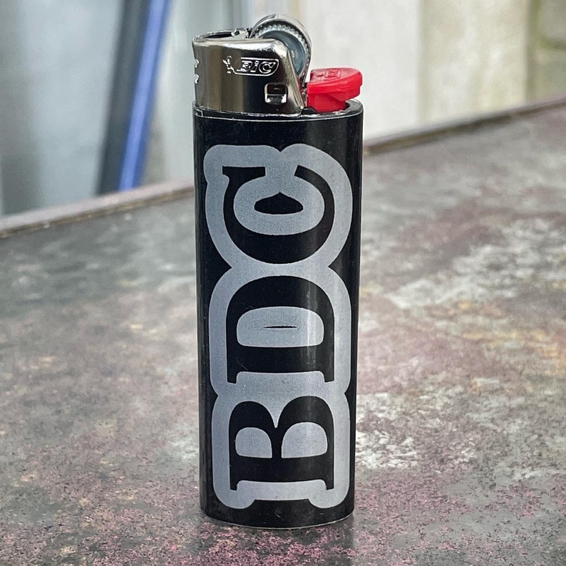 May include: Black lighter with a silver sticker that says "BDC" in a stylised font.