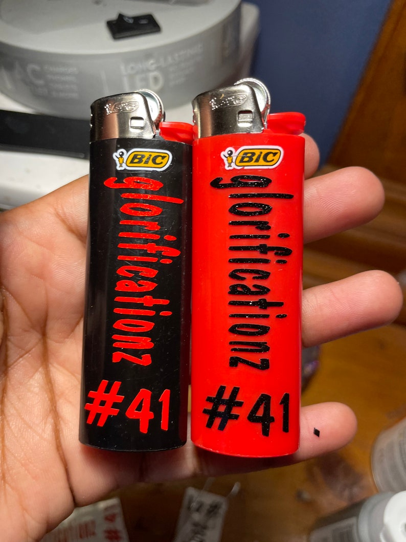 May include: Two red and black lighters with the word "glorification" and the number "#41" printed on them. Both lighters are BIC brand.