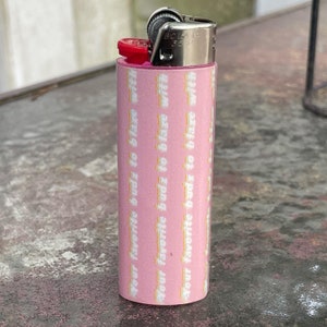 May include: A pink lighter with a white design that says "Your favourite budz to blaze with".