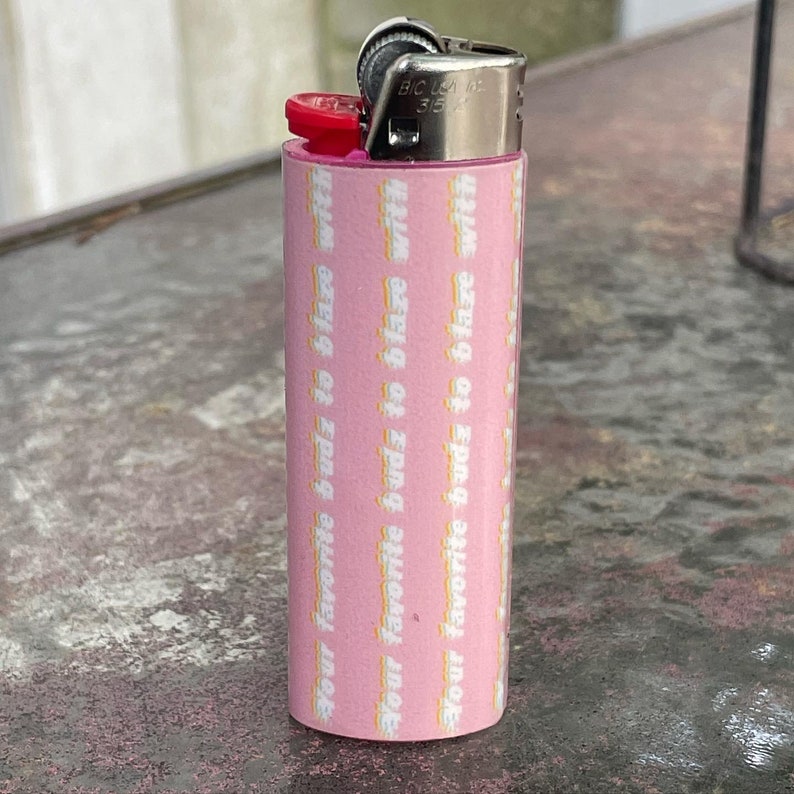 May include: A pink lighter with a white design that says "Your favourite budz to blaze with".
