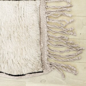 Puede incluir: Una alfombra blanca y esponjosa con un borde de flecos. La alfombra tiene una textura suave y mullida y es perfecta para a&ntilde;adir un toque de calidez y comodidad a cualquier habitaci&oacute;n.