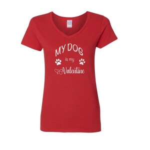 May include: Red V-neck t-shirt with white text that reads "My Dog is my Valentine" with paw prints and hearts.