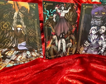 Puede incluir: Tres cartas ilustradas con fondo negro y borde dorado. Cada carta presenta una escena diferente con varios personajes. La primera carta muestra a una mujer con un vestido morado siendo controlada por cuerdas. La segunda carta muestra a una mujer con una chaqueta marrón siendo sostenida por una gran figura negra. La tercera carta muestra a dos personas atadas por un gran gato morado.