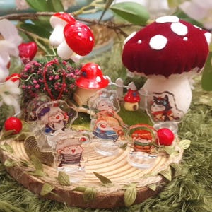 May include: A collection of six miniature figurines of characters with different hairstyles and clothing, displayed on a wooden base with a mushroom and other decorative elements. The figurines are made of clear plastic and have a painted finish.