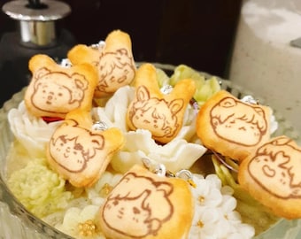 May include: A glass bowl filled with white and green floral arrangements.  The bowl is decorated with small, brown, cartoon-like animal charms.