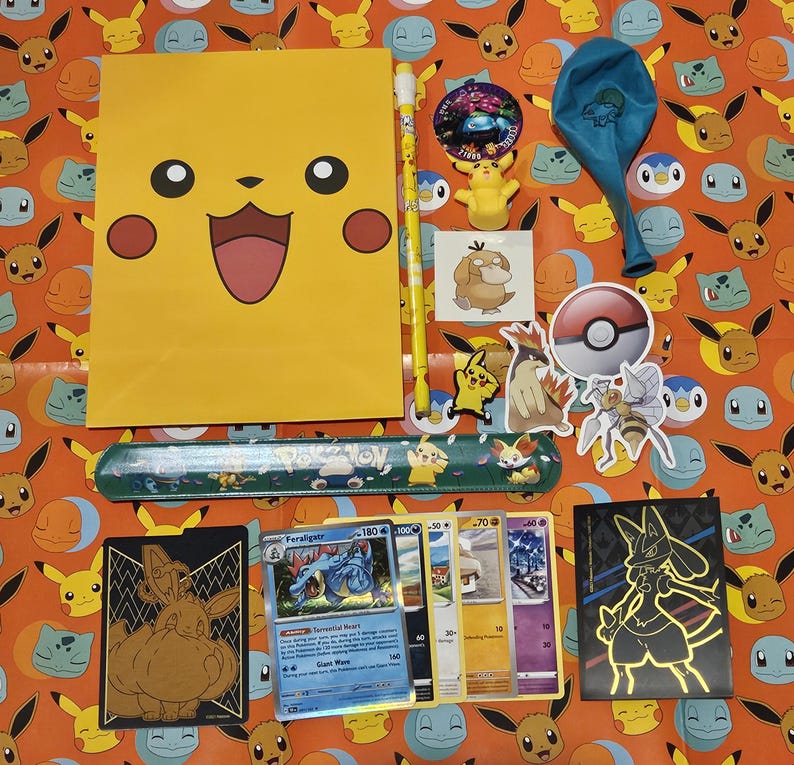 May include: A collection of Pokemon-themed items including a yellow folder with a Pikachu face, a blue ruler, a set of trading cards, a blue balloon, and stickers.