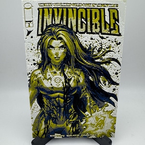 May include: A comic book cover featuring a woman with long, flowing black hair and a yellow and blue costume. The cover is titled "Invincible" and has a grunge-style background.