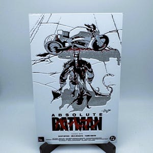 May include: A silver and black comic book cover with the title "Absolute Batman" and a black and white illustration of Batman standing in front of a motorcycle. The motorcycle is partially obscured by a silver background.