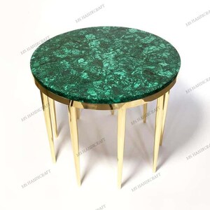 Puede incluir: Una mesa redonda con una tapa de malachite verde y una base de metal dorado. La mesa tiene seis patas y tiene un diámetro de aproximadamente 61 cm.