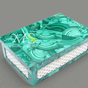 Puede incluir: Una caja decorativa de malaquita verde con un diseño de celosía blanca en la parte delantera. La caja está hecha de piedra natural y tiene un patrón único.